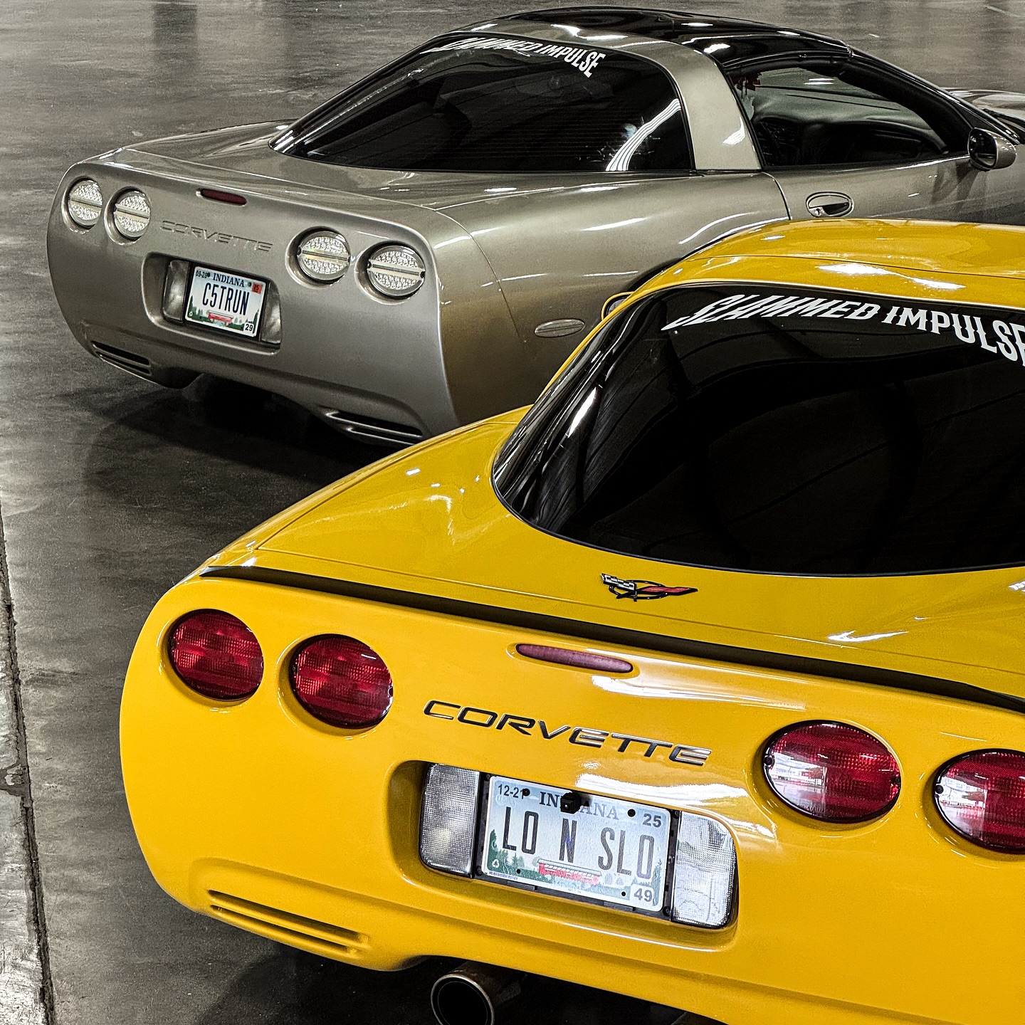 Silver and yellow Corvettes together at a car show